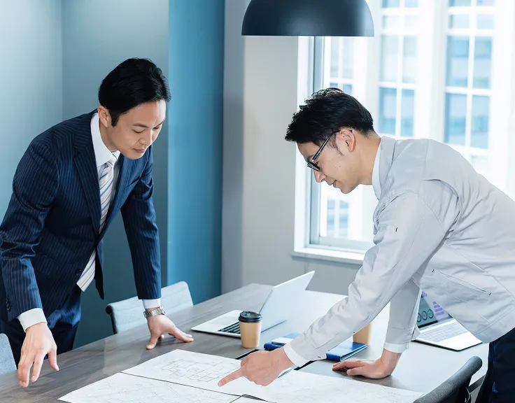業者とスタッフが机に書類を置いて打ち合わせしている風景
