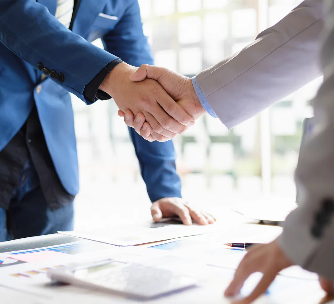 売買仲介で契約の取引を行い取引先様とスタッフが握手している