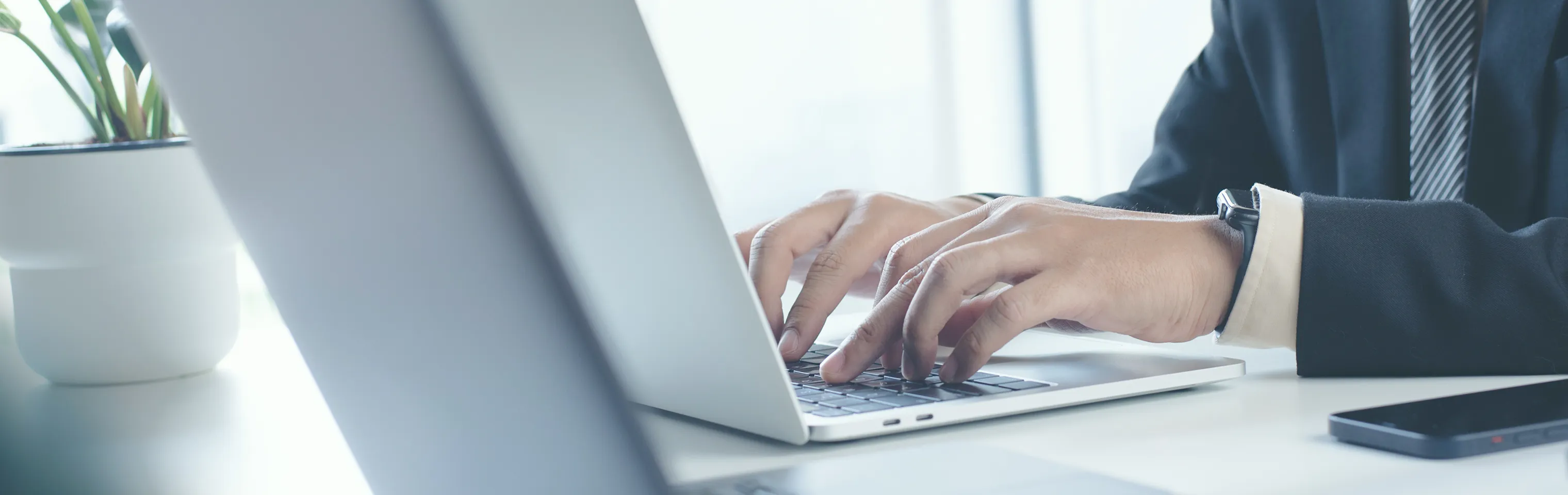 男性がデスクでパソコンを開いてタイピングしている風景