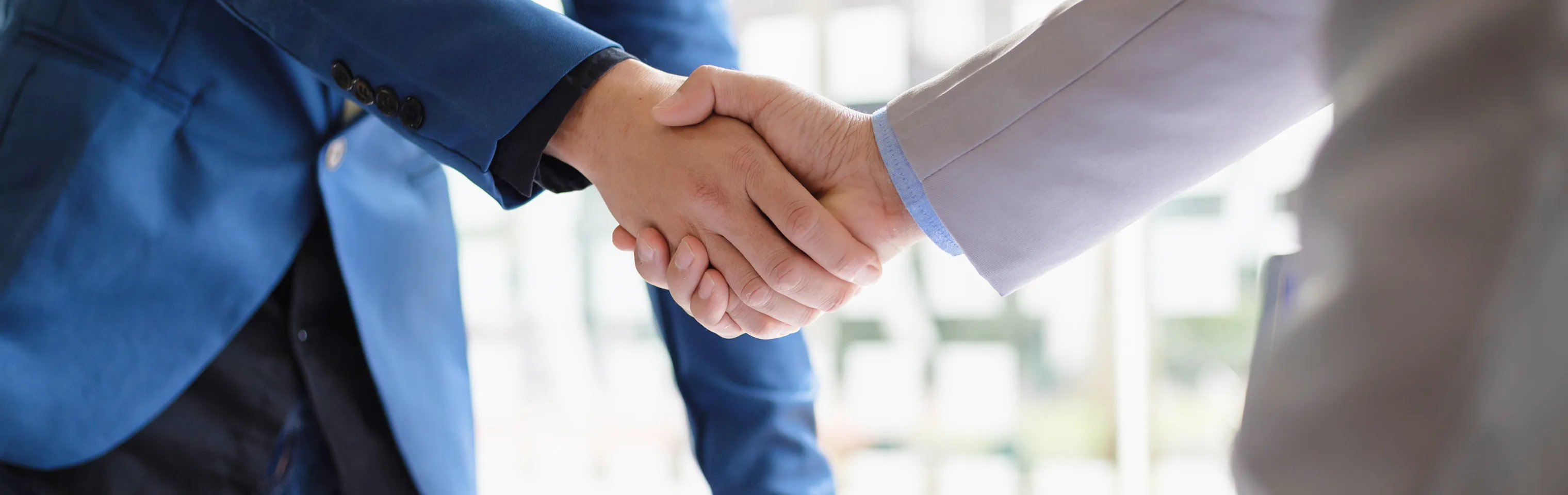 売買仲介で契約の取引を行い取引先様とスタッフが握手している
