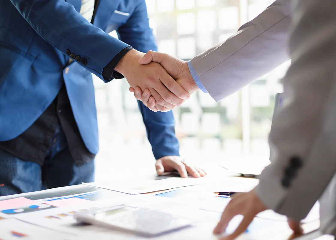 売買仲介で契約の取引を行い取引先様とスタッフが握手している